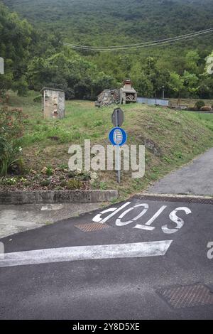 Stop sign on a descending road in the mountain Stock Photo