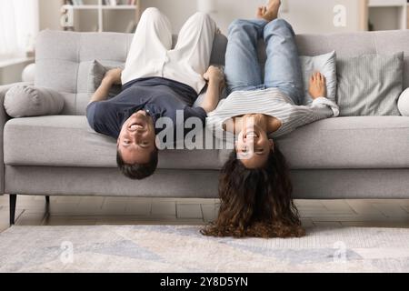 Happy carefree young couple resting upside down on comfortable couch Stock Photo