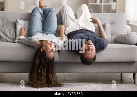 Cheerful cute young couple relaxing on grey soft couch Stock Photo