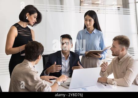 Confident Indian business leader man talking to diverse team Stock Photo