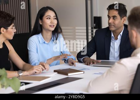 Positive young Asian project manager presenting marketing strategy to colleagues Stock Photo