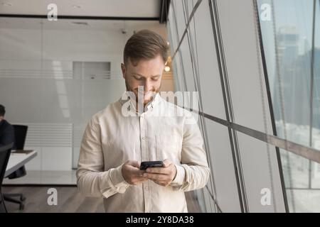 Positive focused young businessman in casual using financial application Stock Photo