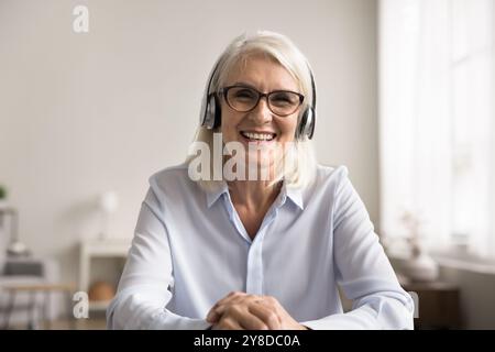 Woman sitting at table engaged in videocall or online meeting Stock Photo