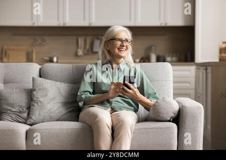 Happy smiling mature woman using smartphone at home Stock Photo