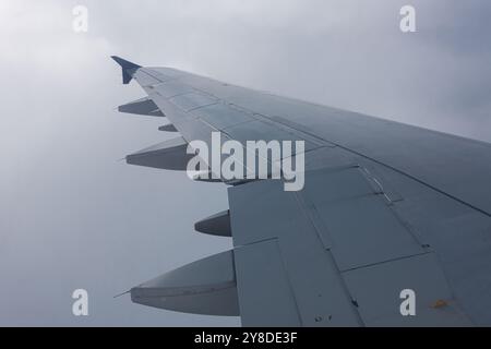 View of the airplane wing in the fog, with air traffic above the clouds in the background Stock Photo