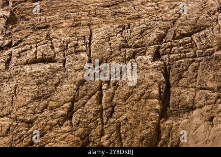 Close-up of a textured rock surface with visible cracks and layers. Stock Photo