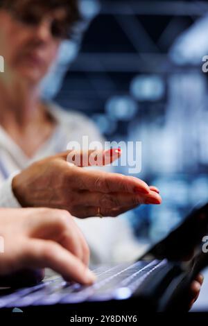 Colleagues performing diagnostic assessments on mainframes to detect problems with server room units. Coworkers crosschecking maintenance lists, looking for potential system concerns, close up Stock Photo