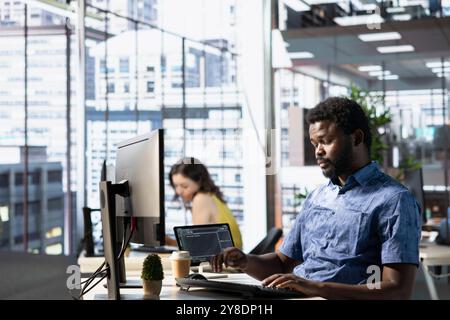 System administrator conducting detailed code review to fix bugs, identifying potential performance and technical issues with company software. African american man debugging and optimizing code Stock Photo
