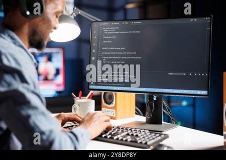 On terminal window, african american internet programmer writes server code in binary and machine language. Fixing security issues of databases as a young network engineer, remote work. Stock Photo