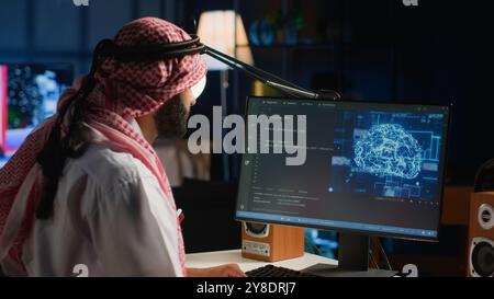 Experienced Arab developer programming scripts on computer screen, employing AI machine learning, manipulating lines of code for artificial intelligence applications computing Stock Photo