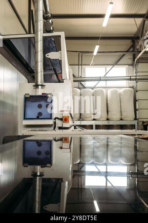 A large industrial machine with a dust collection system operates in a furniture manufacturing facility. Stock Photo