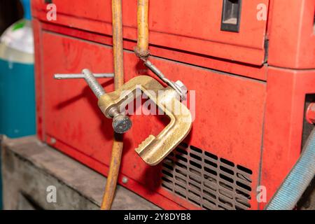 Photograph of an old and damaged earth clamp and cable on a welding machine in a factory. Stock Photo