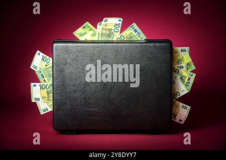 A briefcase overflowing with euro banknotes. Concept studio shot on illuminated burgundy red background with dark vignette Stock Photo
