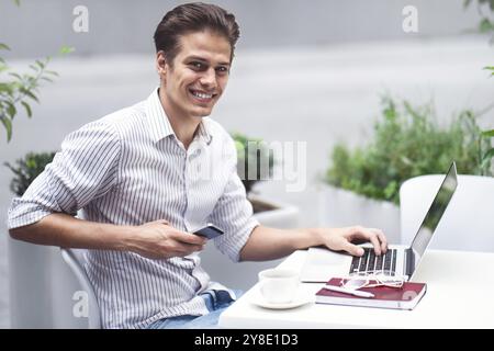 Smart attitude. Positive handsome man using a laptop and sitting in the cafe while surfing the internet Stock Photo