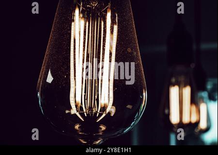Glowing Edison-style light bulb in dark surroundings creates a warm atmosphere Stock Photo