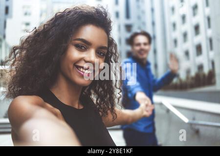 Outdoor portrait beautiful happy afroamerican woman taking selfie photograph smiling laughing with perfect teeth at street Stock Photo