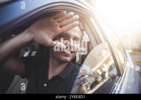 Image of young handsome guy sitting in car and meet someone Stock Photo