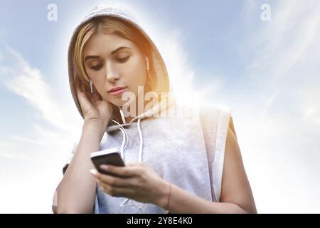 Beautiful young woman with headphones glad after nice jogging in city park Stock Photo