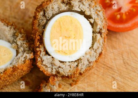 Simply arranged and ready to eat,with fresh sliced tomato, on a wooden chopping board with loose bread crumbs falling off onto the wood suface. Stock Photo