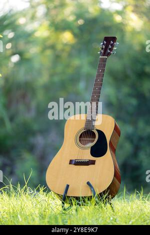 Acoustic guitar outdoors on greenery background. Concept of calm music. Stock Photo