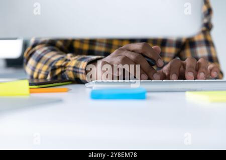 Front view mid section of a young African American man sitting at a desk using a computer in the modern office of a creative business Stock Photo