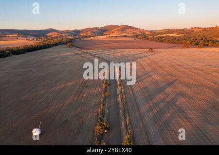 Aerial view of a country road cutting through dry farmland with early morning shadows at Wilmington in South Australia, Stock Photo