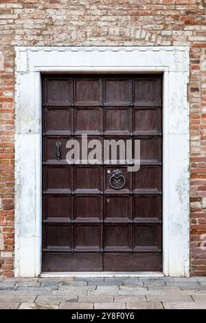 Door in red brick wall in Venice. Italy. Ancient facade. Vintage wooden door in old red brick building in Venice, Italy. Stock Photo