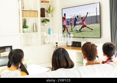 Diverse group of children watching football match siting together on the couch. Sport, competition and cheering together. Stock Photo