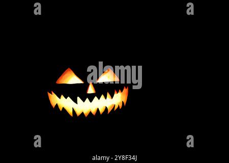 Scary Halloween pumpkin with glowing eyes at black background. Spooky Halloween pumpkin, Jack O Lantern, with an evil face, smile and eyes on black ba Stock Photo