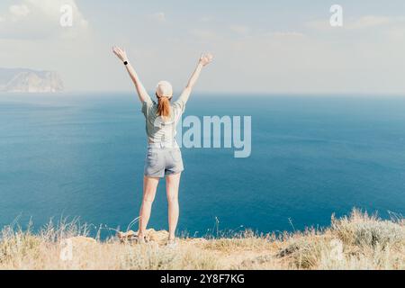 Woman Celebrating on a Clifftop with a View of the Sea Stock Photo
