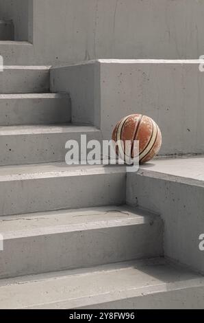 Old basketball ball on cement floor with Stairs leading and Natural light. use it as your Wallpaper, Poster and Copy space, Selective focus. Stock Photo