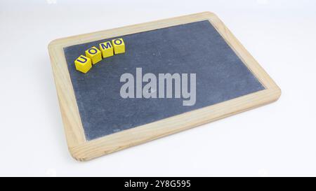 The world MAN in Italian written on wooden cubes. Someone puts in place the writing with black slate board Copy space Stock Photo