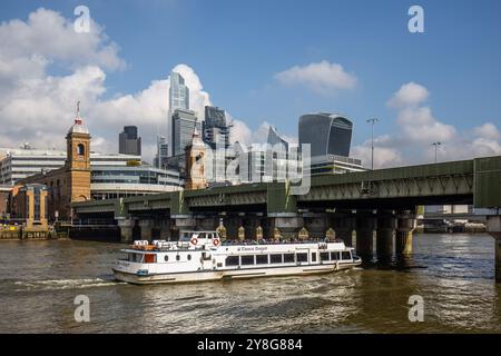 The Thomas Doggett Pleasure Boat takes passengers under Canon Bridge Station to the East of London towards Greenwich.Blue skies and a sunny day ! Stock Photo