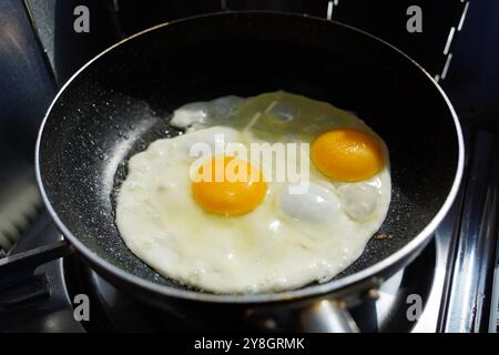 Fried eggs in a frying pan on a gas stove in the kitchen Stock Photo