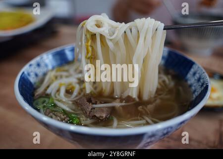 Vietnamese rice noodles in a bowl with chopsticks on a wooden table Stock Photo