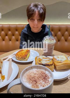 Boy having lunch in a Starbucks coffee shop with cinnamon rolls for dessert Stock Photo