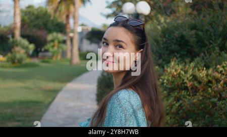 A woman with long hair is walking in a park Stock Photo
