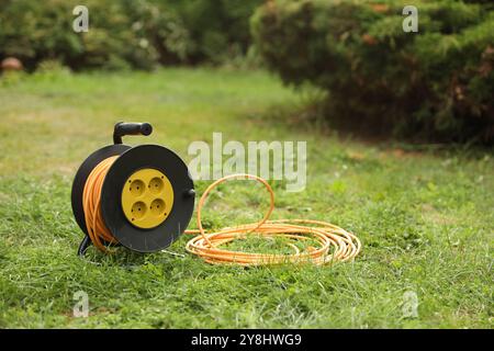 Extension cord reel on green grass outdoors Stock Photo