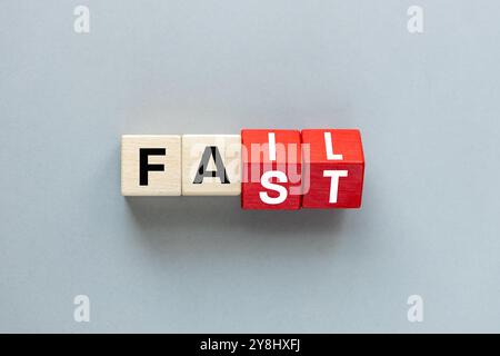 FAIL and FAST concept. letters on wooden blocks changing the word fast to fail, concept, beautiful gray background. flat lay, copy space Stock Photo