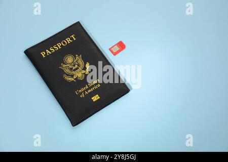 Modern SIM card and passport on light blue background Stock Photo