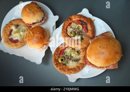 A close-up selection of traditional savory aperitivo snacks including mini pizzas and prosciutto ham sliders at a restaurant in Parma, Italy. Stock Photo