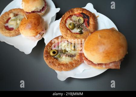 A close-up selection of traditional savory aperitivo snacks including mini pizzas and prosciutto ham sliders at a restaurant in Parma, Italy. Stock Photo