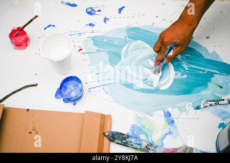 close up of hand holding paintbrush mixing colour on the palette Stock Photo