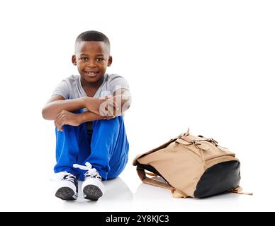Kid, boy and portrait with backpack in studio for back to school, mockup space or happy for education on floor. Student, black child and smile with sc Stock Photo