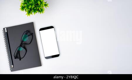 Top view of mock up modern workspace with blank screen smartphone, Coffee cup, Notebook, Pencil, Glasses. Office situation with keyboard and accessori Stock Photo