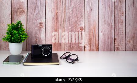 Mock up modern home decor with camera, Houseplant, Phone, Notebook, Glasses. Artist workspace with copy space for products display montage. Stock Photo
