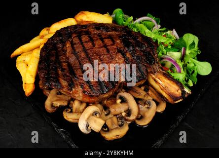 Cote de boeuf beef rib steak meal with chips and fried mushrooms Stock Photo
