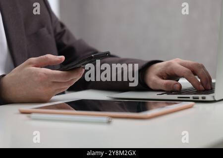 Businessman using different devices at white table indoors, closeup. Modern technology Stock Photo