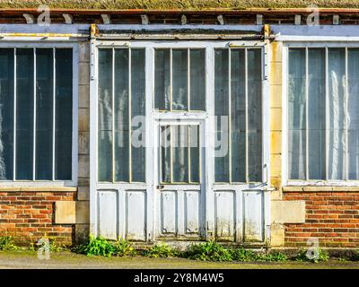 Old sliding door and windows on front of former commercial business - La Trimouille, Vienne (86), France. Stock Photo