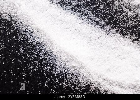 Macro crystals of white rock edible salt on black background. Stock Photo